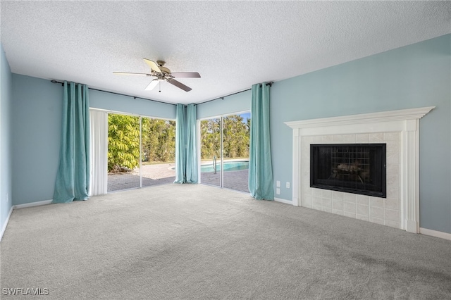 unfurnished living room with a tiled fireplace, carpet, a textured ceiling, and ceiling fan