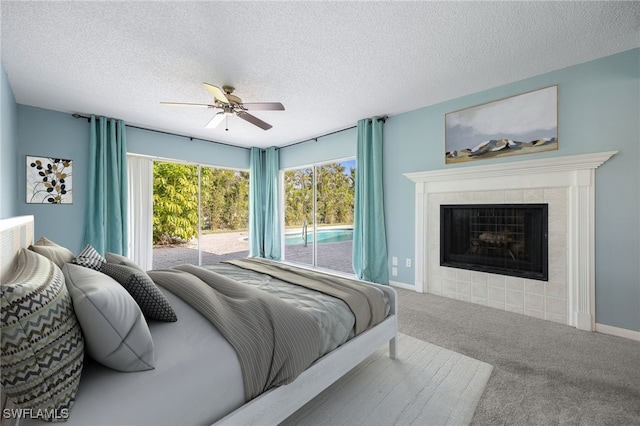 bedroom featuring a tile fireplace, carpet flooring, a textured ceiling, and ceiling fan