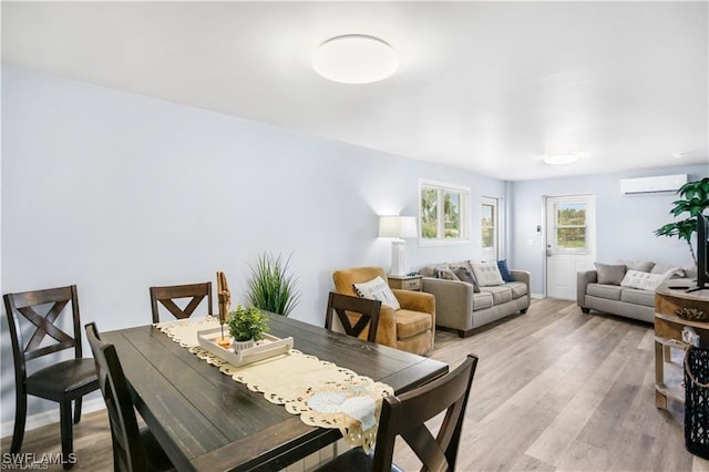 dining room with light hardwood / wood-style floors and an AC wall unit