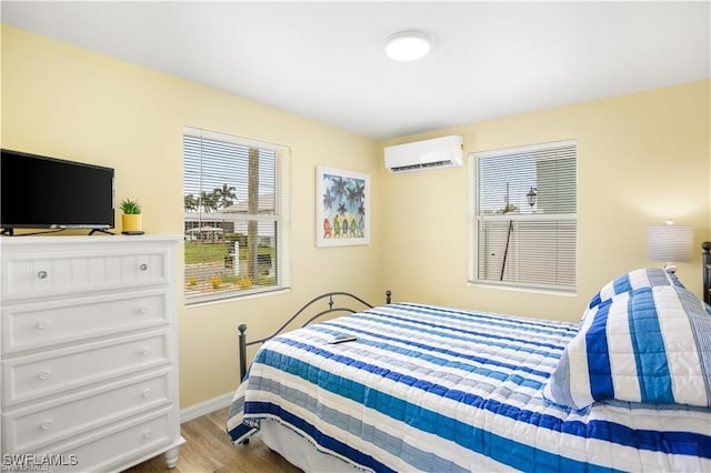 bedroom with light hardwood / wood-style flooring and an AC wall unit