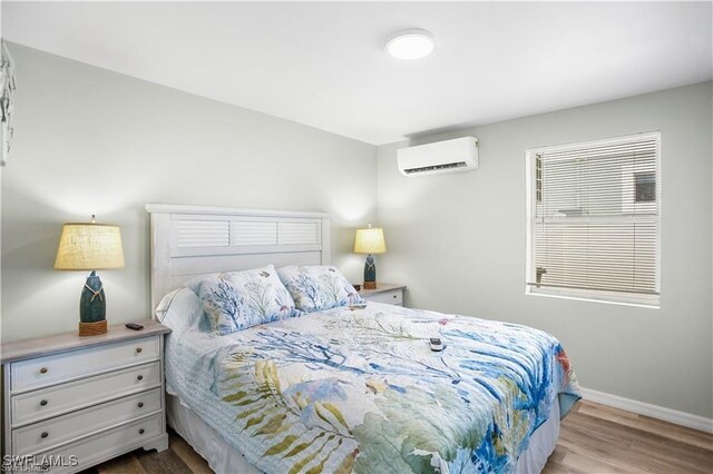 bedroom with hardwood / wood-style flooring and an AC wall unit