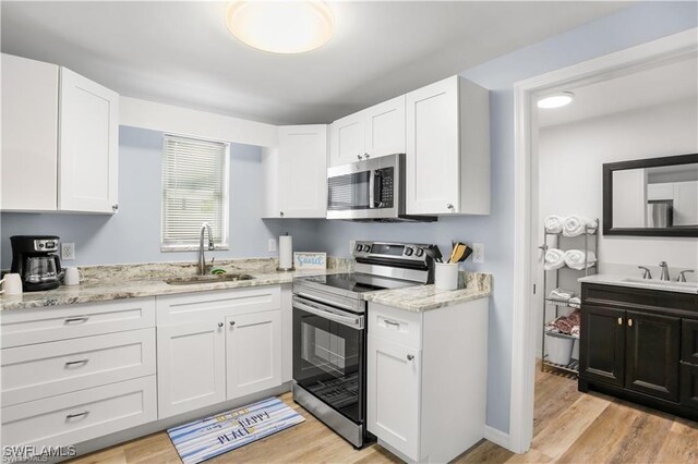 kitchen with white cabinets, appliances with stainless steel finishes, light wood-type flooring, and sink