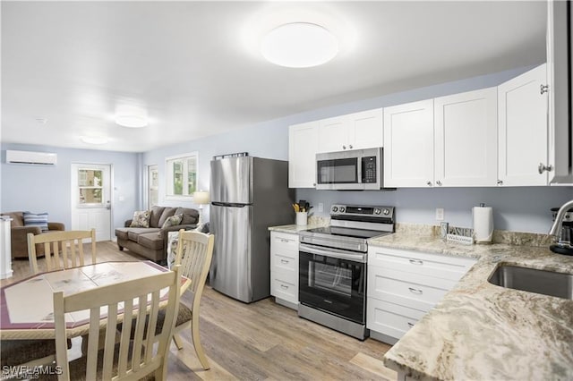 kitchen featuring stainless steel appliances, white cabinetry, an AC wall unit, and sink