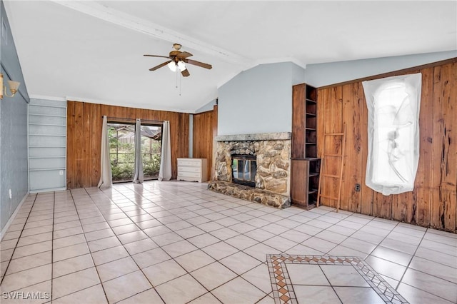 unfurnished living room with built in shelves, ceiling fan, light tile patterned floors, a stone fireplace, and wood walls