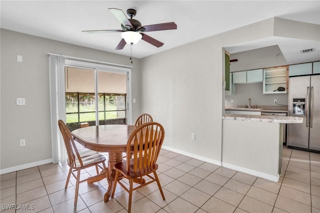 tiled dining space with ceiling fan and sink