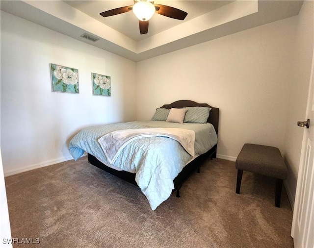 carpeted bedroom with ceiling fan and a tray ceiling