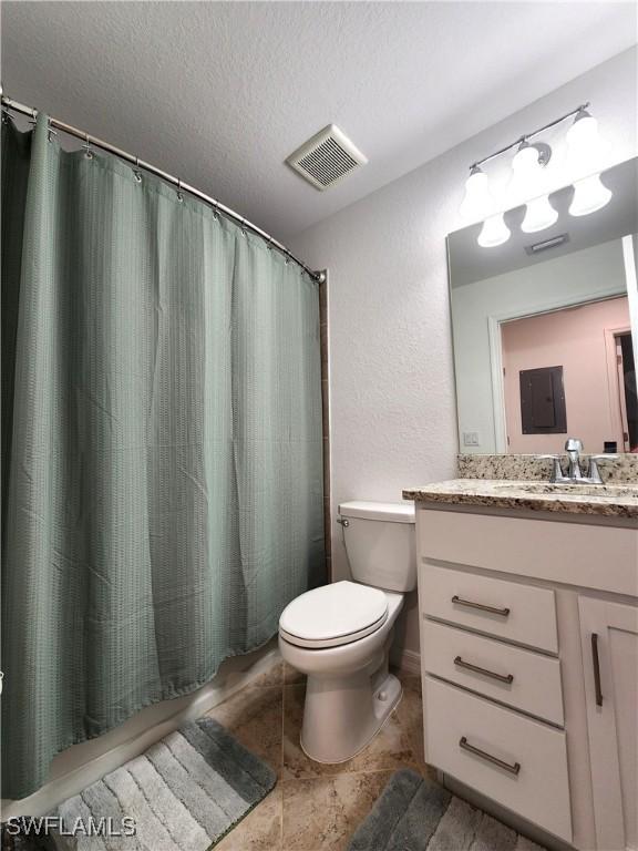 bathroom featuring a textured ceiling, toilet, vanity, and a shower with curtain