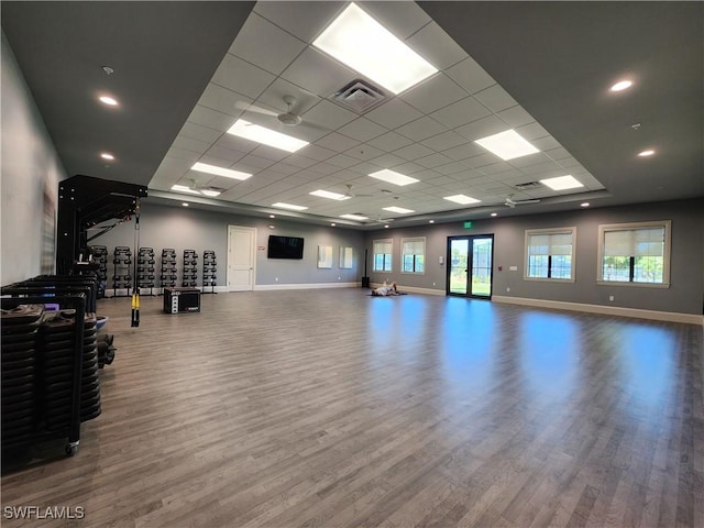 workout area with wood-type flooring, a paneled ceiling, and plenty of natural light