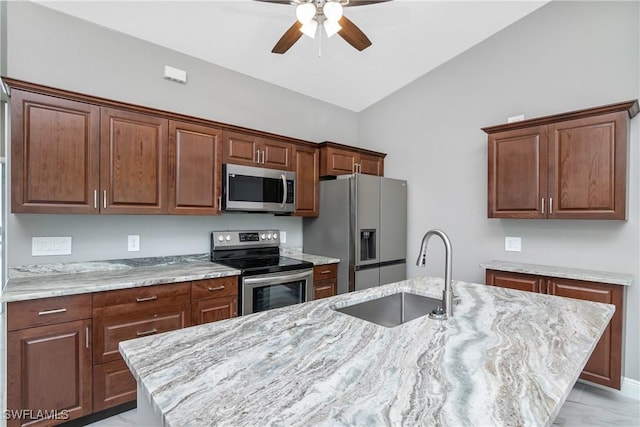 kitchen featuring light stone counters, an island with sink, appliances with stainless steel finishes, ceiling fan, and sink