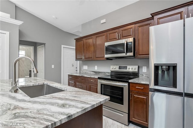 kitchen featuring appliances with stainless steel finishes, lofted ceiling, light stone counters, and sink