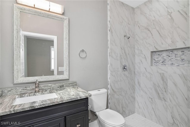 bathroom with toilet, a tile shower, and vanity