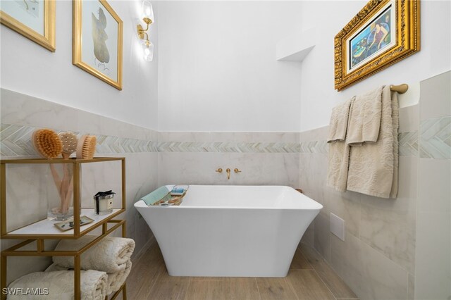 bathroom featuring tile walls, a bathtub, and hardwood / wood-style flooring