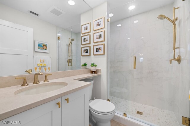 bathroom featuring vanity, a shower with door, and toilet