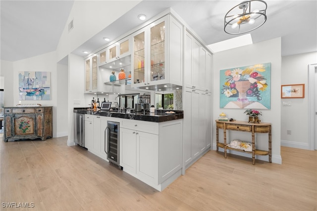 bar with white cabinetry, beverage cooler, and light wood-type flooring