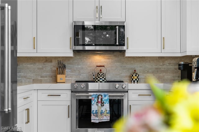 kitchen featuring stainless steel appliances, tasteful backsplash, and white cabinets