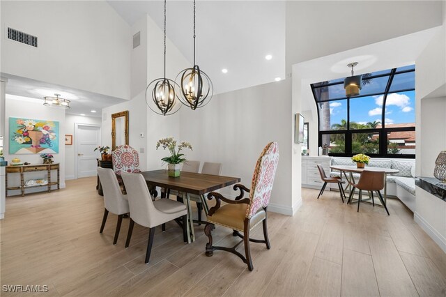 dining area featuring a notable chandelier, light hardwood / wood-style flooring, and a high ceiling