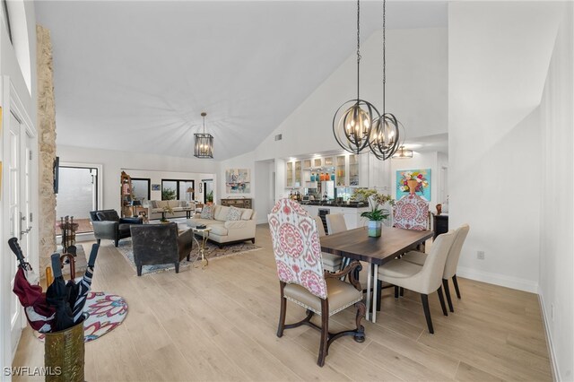 dining space featuring high vaulted ceiling, an inviting chandelier, and light hardwood / wood-style floors