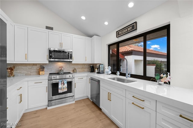 585 Bay Villas Ln Unit 88, Naples, FL 34108 - kitchen with vaulted ceiling, a sink, stainless steel appliances, backsplash, and visible vents