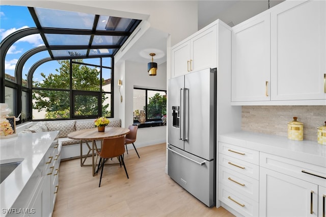 kitchen with pendant lighting, white cabinets, breakfast area, high end fridge, and light wood-type flooring