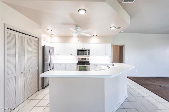 kitchen with appliances with stainless steel finishes, a kitchen island with sink, light tile patterned floors, and white cabinets