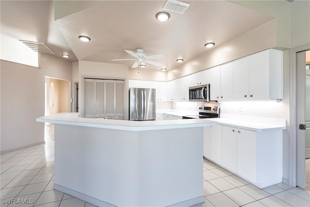 kitchen with a kitchen island with sink, light tile patterned floors, white cabinets, and appliances with stainless steel finishes