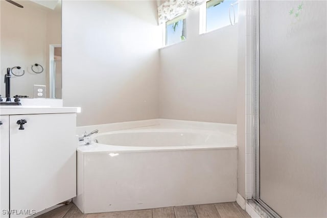 bathroom with vanity, a bath, wood finished floors, and an enclosed shower