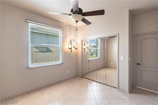 unfurnished bedroom featuring light tile patterned floors, a closet, baseboards, and ceiling fan