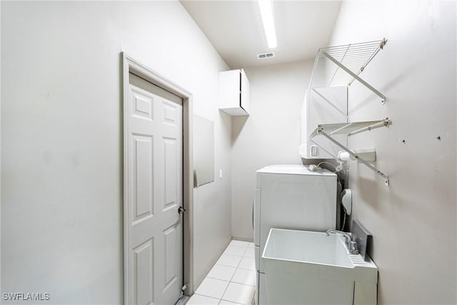 clothes washing area featuring a sink, visible vents, cabinet space, and light tile patterned flooring