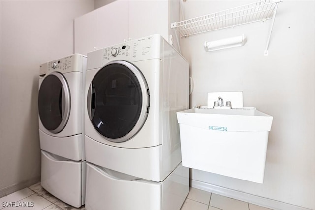 laundry area with washing machine and clothes dryer, laundry area, baseboards, and a sink