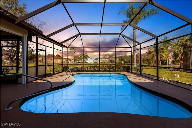 pool at dusk featuring an outdoor pool, a patio, and a lanai