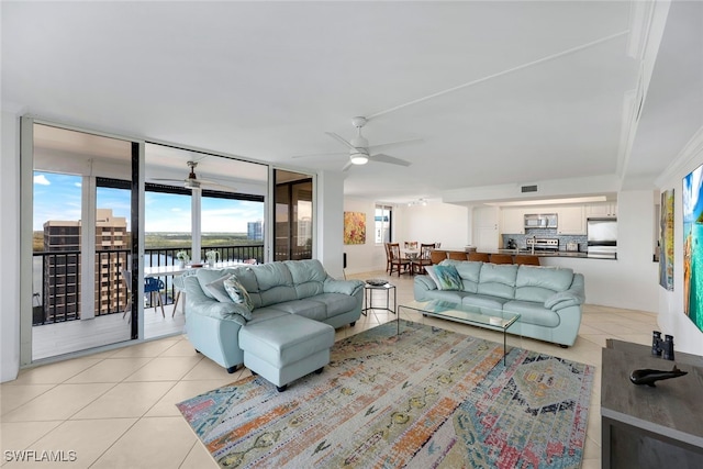 living room featuring expansive windows, a water view, ceiling fan, and light tile patterned flooring