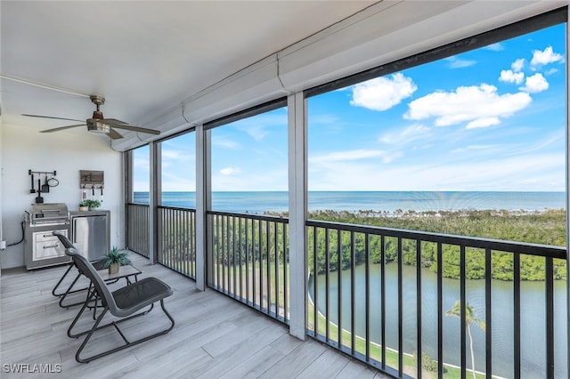 sunroom / solarium with a water view and ceiling fan