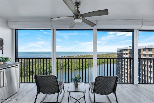 sunroom / solarium featuring a water view and ceiling fan