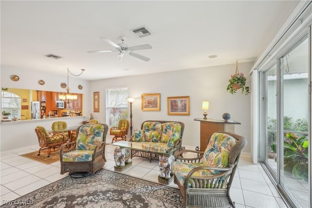 tiled living room featuring ceiling fan with notable chandelier