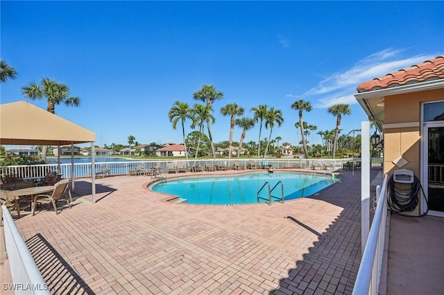 view of pool featuring a water view and a patio area