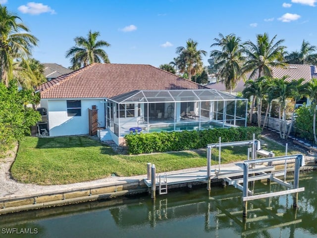 rear view of house with a lanai, a yard, and a water view