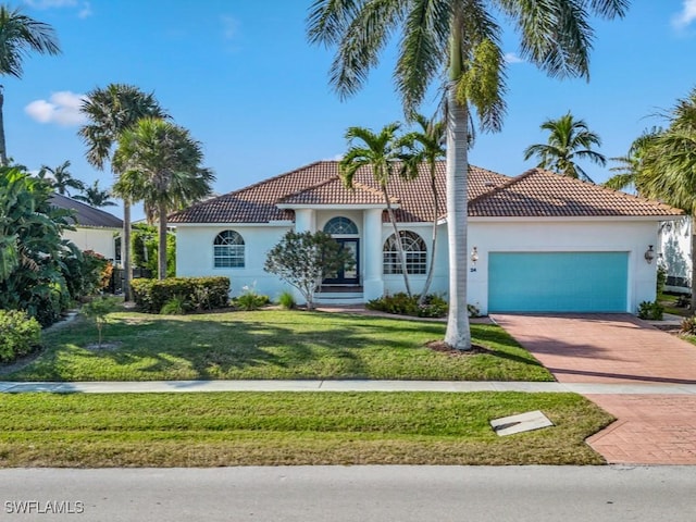 mediterranean / spanish-style home with a garage and a front lawn