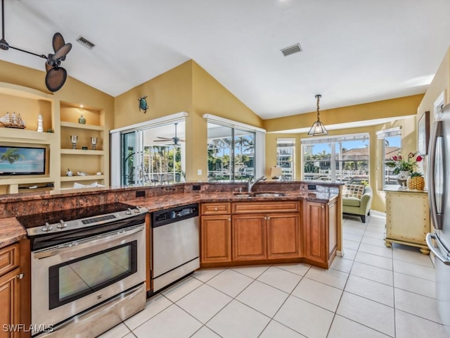 kitchen with stainless steel appliances, built in features, dark stone counters, pendant lighting, and vaulted ceiling