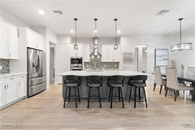 kitchen with pendant lighting, appliances with stainless steel finishes, and a center island with sink