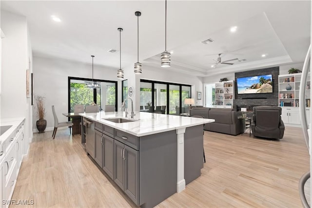 kitchen with ceiling fan, a tray ceiling, decorative light fixtures, light stone countertops, and sink