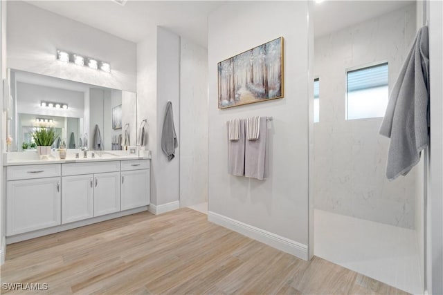 bathroom featuring a tile shower, hardwood / wood-style flooring, and vanity