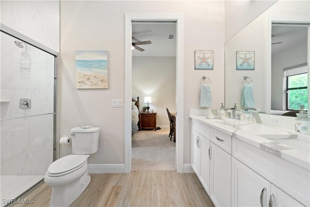 bathroom with toilet, vanity, ceiling fan, wood-type flooring, and an enclosed shower