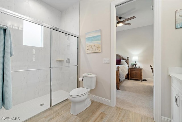 bathroom with ceiling fan, vanity, toilet, hardwood / wood-style flooring, and a shower with door