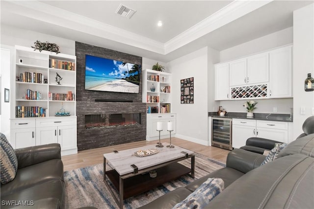 living room with a fireplace, light wood-type flooring, bar area, and beverage cooler