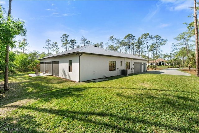 back of house with a lawn, cooling unit, and a garage