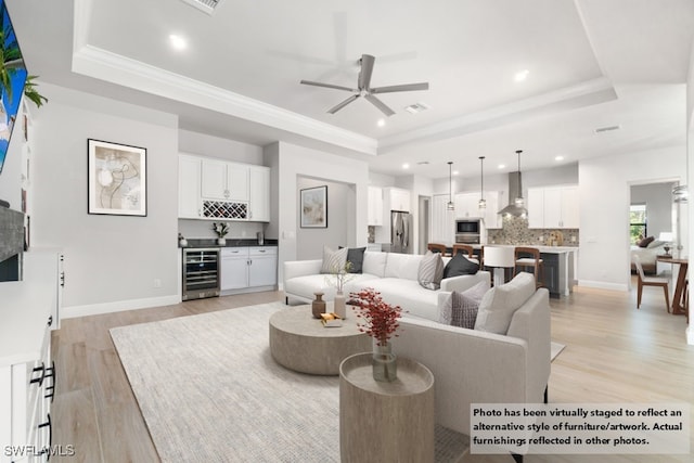 living room featuring light hardwood / wood-style floors, a raised ceiling, ceiling fan, and wine cooler