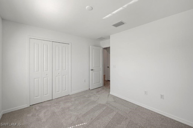 unfurnished bedroom with light carpet and a closet