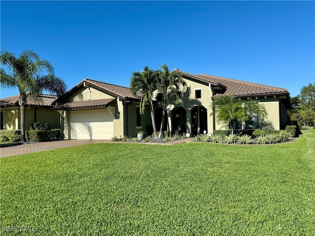 mediterranean / spanish home featuring a garage and a front lawn