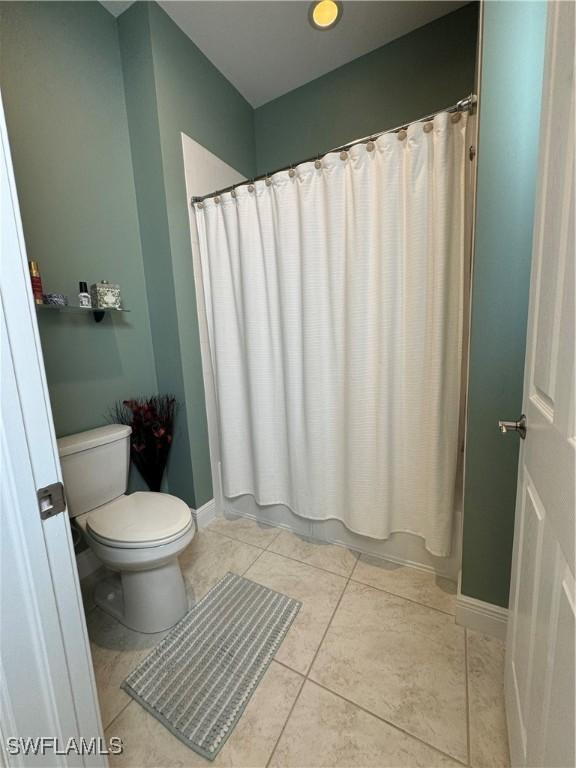 bathroom featuring toilet, tile patterned flooring, and shower / tub combo