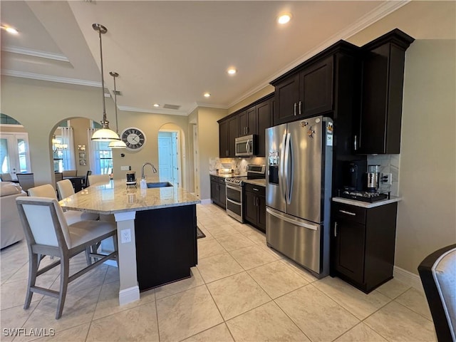 kitchen with a breakfast bar, light tile patterned flooring, a kitchen island with sink, and appliances with stainless steel finishes